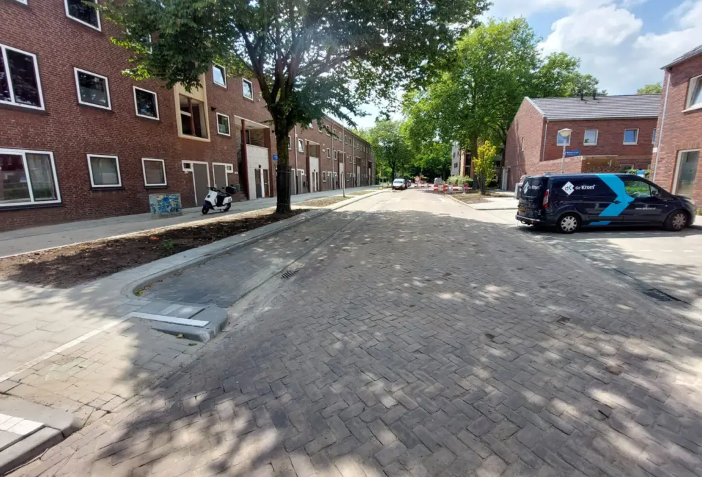 Opnieuw bestrate woonstraat met bomen en woningen